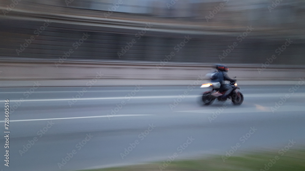 The photo shows a person riding a motorcycle, but due to blurriness, it is difficult to make out the details.