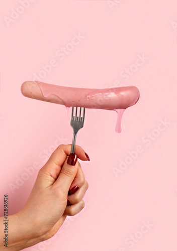 Hot sausages with pink sauce on fork pink background.