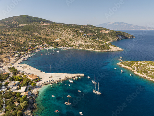 Fototapeta Naklejka Na Ścianę i Meble -   Port on a Greek island with blue turquoise water with many boats and yachts on the water in Greece, Zakynthos. Aerial drone photo of Agios Nikolaos - a small port on the island of Zante.