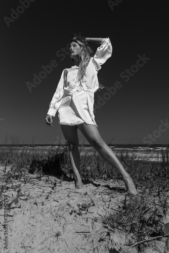 young beautiful woman model on the beach in a dress in a fashion photosoot photo