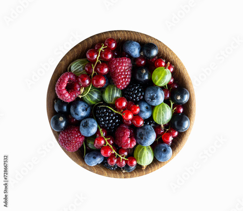Different berries and fruits in a bowl. Top view. Mixed berries isolated in wooden bowl on white background. Blueberry, blackberry, raspberries, blackcurrant, red currants and gooseberry.