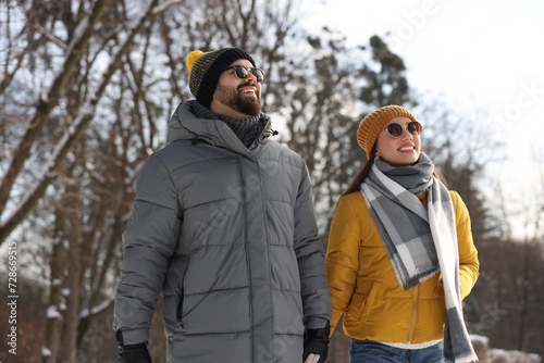 Beautiful happy couple walking in snowy park on winter day