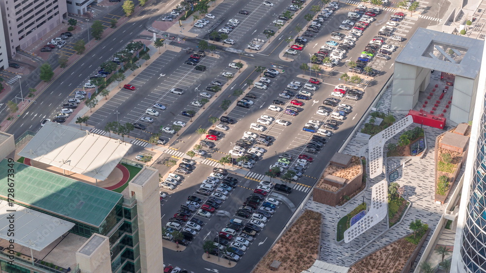 Fototapeta premium Aerial view of many colorful cars parked on parking lot with lines and markings for parking places all day timelapse. Dubai