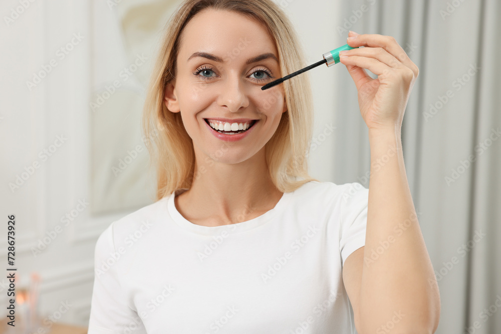 Beautiful woman applying mascara with brush indoors Beautiful woman applying mascara with brush indoors