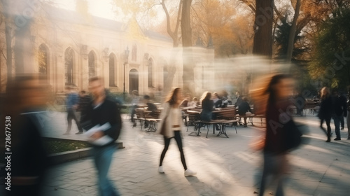 Abstract blur of people walking down a busy city street. Movement of students walking. Unfocused cafes and buildings.