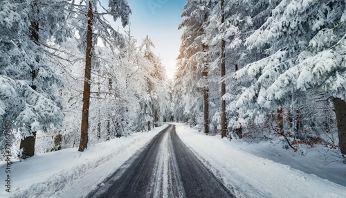empty frozen road through idyllic snowy forest in winter