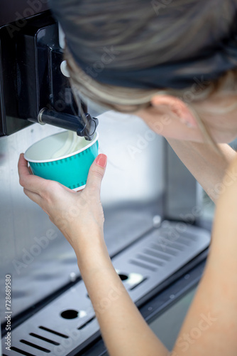 Closeup of a young beautiful woman serving a cup of smooth ice cream yogurt gelato