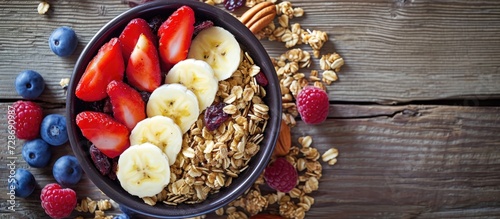 Fruit bowl with dry fruit, granola on wooden surface.