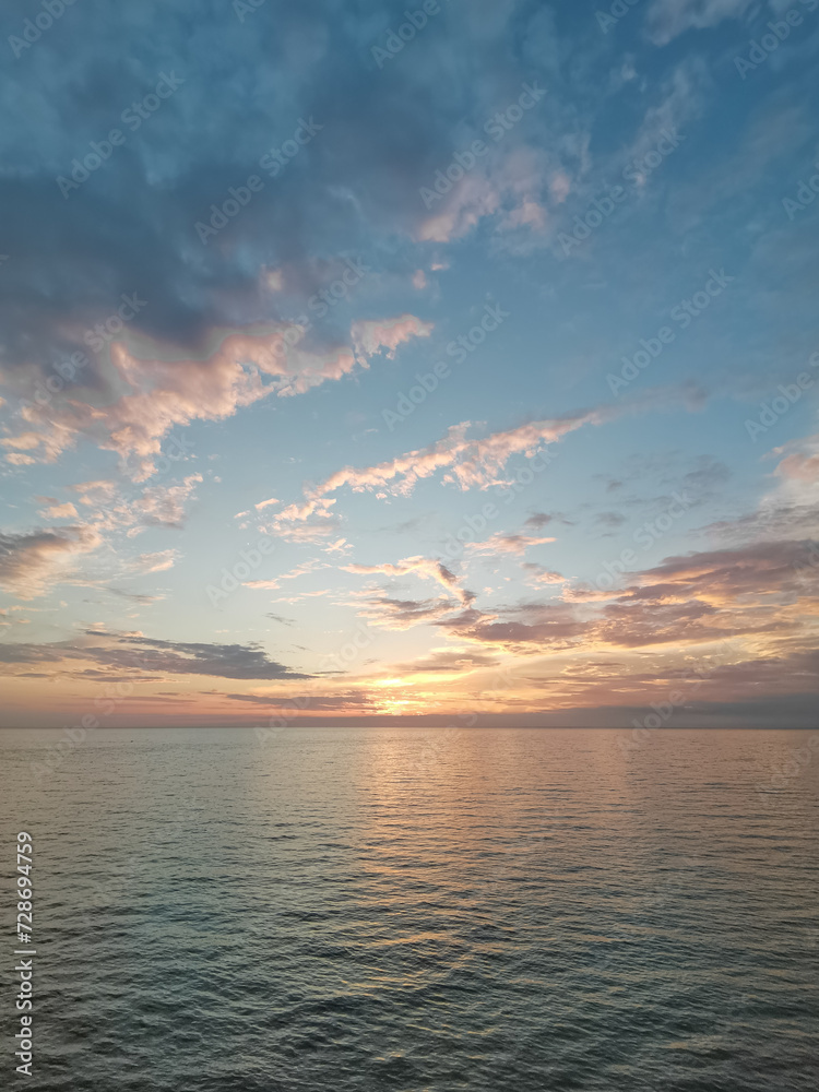 Tranquil Evening Seascape, Summer Sunset Casting Warm Glow Over Calm Waters with Clouds, Serene Beauty of Dusk