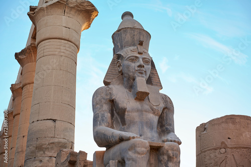 Seated statue of Ramesses II by the First pylon of the Luxor Temple, Egypt. Columns and statues of the Luxor temple main entrance, first pylon, Egypt