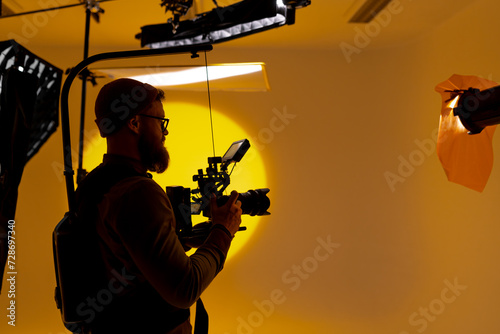 Foto Back angle view of high definition digital video camera which recording or shooting tv commercial production on pan tilt shift professional head tripod at outdoor location and film crew team with set