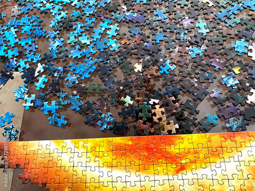 partially solved puzzle with colorful  scrambled pieces over the table