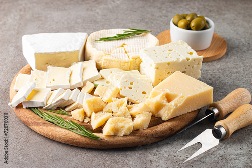 Wooden board with various cheese and olives. Brie. Camembert. Parmesan, feta, blue cheese. Italian, French cheese.
