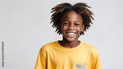 Rostro de niño afro, sonriente, con playera amarilla, sobre fondo blanco photo