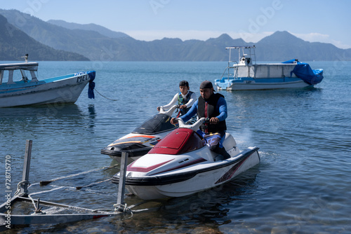 Vászonkép Young Hispanaic Men Lower Jet Skis from Trailer into the Water