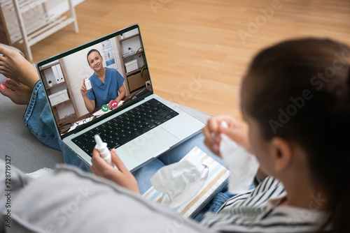 Patient holding medication while video conferencing with a healthcare provider for telemedicine consultation.  photo