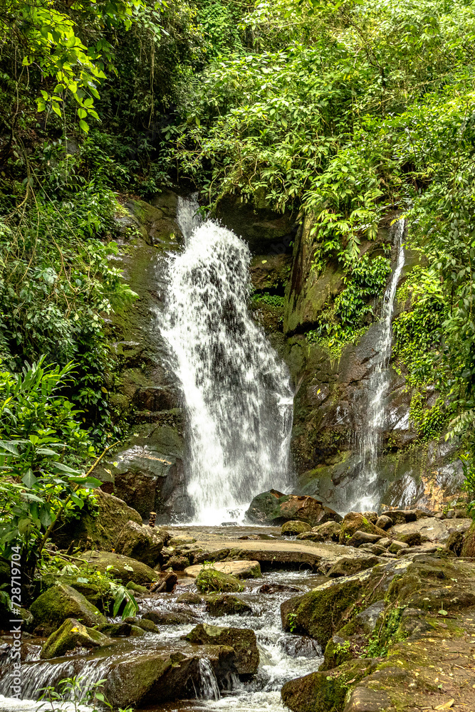 Waterfall running between rocks at the foot of the mountain

Waterfall running between the rocks at the foot of the mountain, creating a winding and refreshing path. The tumultuous water splashes in a