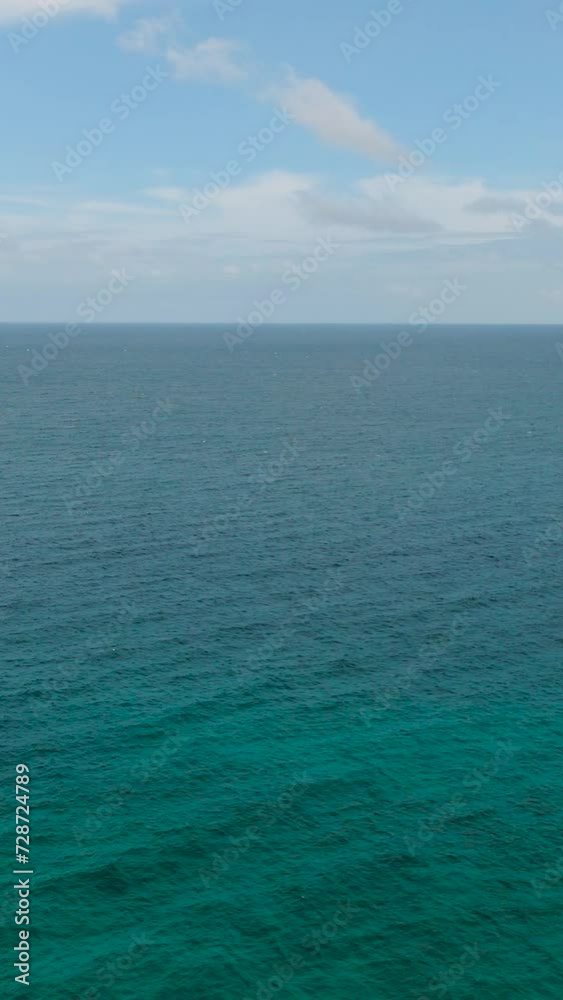 Flying over the turquoise sea water with coral reefs in Carabao Island. Blue sky and clouds. San Jose. Romblon, Philippines. Vertical view. Flying over the turquoise sea water with coral reefs in Carabao Island. Blue sky and clouds. San Jose. Romblon, Philippines. Vertical view.