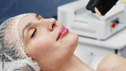 Laser hair removal, young woman's face. A cosmetologist applies ultrasound gel to a woman's face before epilation. A cosmetologist prepares a woman's skin for laser hair removal. photo