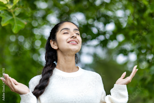 Photography Close-up photo of a beautiful Indian woman standing in a park in a white sweater