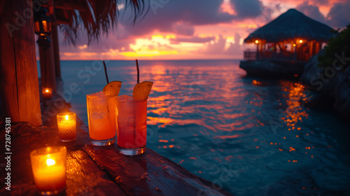 View from a beautiful oceanfront hut at sunset with candles and tropical cocktails, tiki bar, tiki hut, island vacation escape, desert island, pink, blue, purple, orange, ocean, beach, palm trees