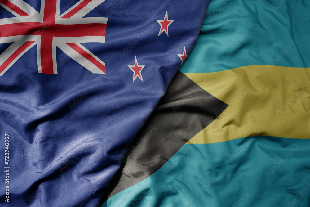 big waving national colorful flag of bahamas and national flag of new zealand .