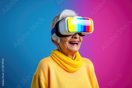 Smiling senior woman wearing virtual reality against pink and blue background