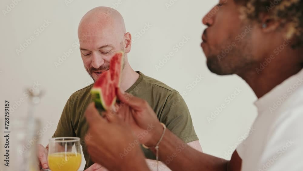 A diverse same-sex male couple shares a moment of joy while eating a nutritious breakfast in a well-lit room, signifying togetherness and a healthy lifestyle. A diverse same-sex male couple shares a moment of joy while eating a nutritious breakfast in a well-lit room, signifying togetherness and a healthy lifestyle.