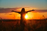 Woman with open arms, facing the sun, letting out her emotions of freedom.