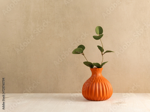 Green leaves branch in vase on wooden table. Copy space. Minimalist interior mock up in scandinavian style.