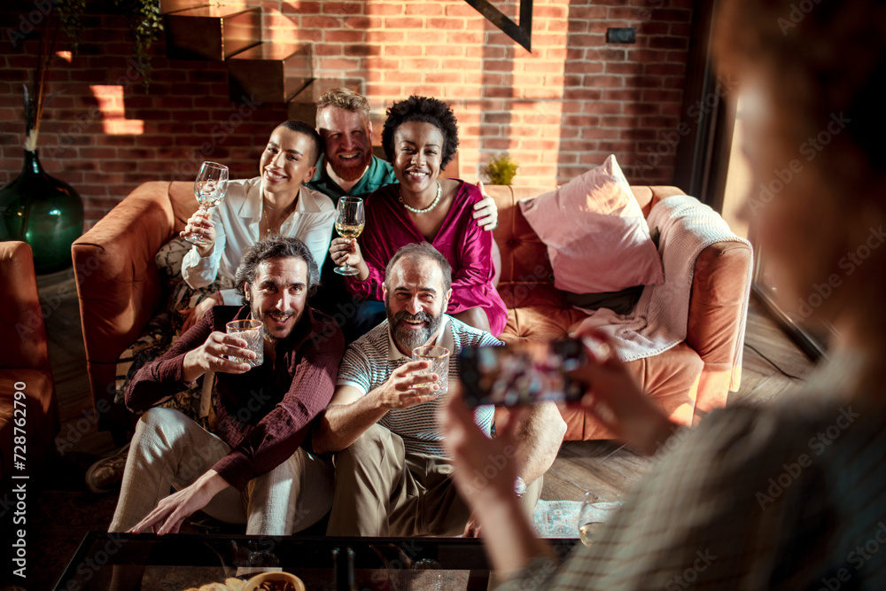 Friends taking a group photo with glasses in a cozy home setting Friends taking a group photo with glasses in a cozy home setting