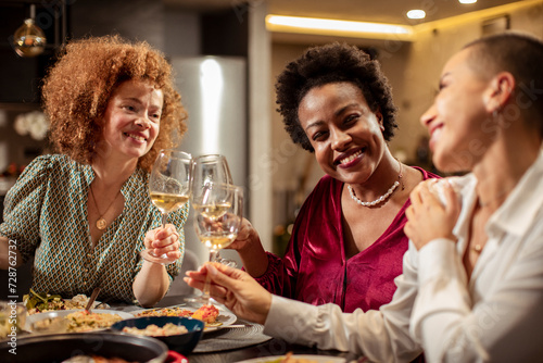 Women toasting with wine glasses at a dinner party photo
