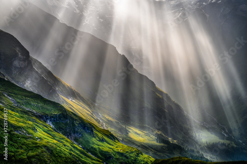 Nature and landscape  in the spring. Landscape with dramatic sky and green meadows. The sun rays through the clouds. The Hohe Tauern mountain range, the valley below the hochalpenrstrasse.
 #728769537