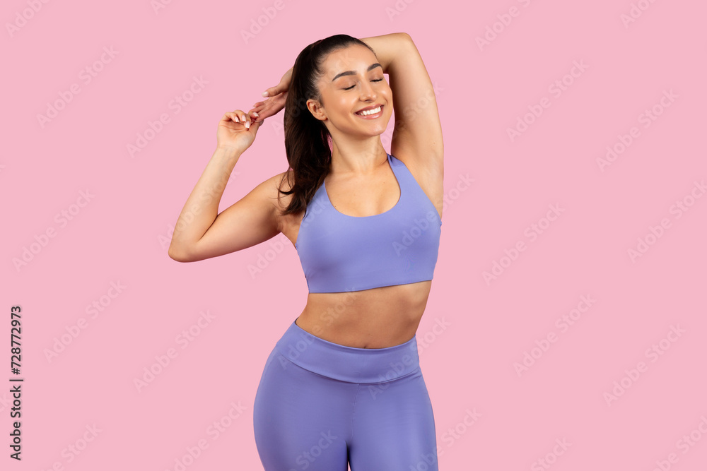 Relaxed athletic woman stretching arms in purple outfit Relaxed athletic woman stretching arms in purple outfit