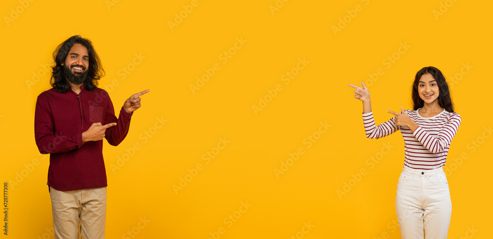 Obraz premium Positive young indian man and woman pointing at blank space