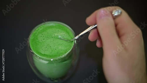 Woman stiring green matcha foam with spoon photo
