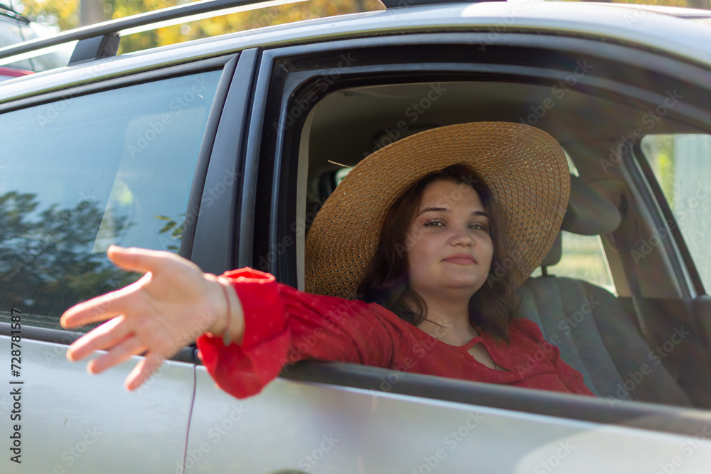 Naklejka premium Girl in hat sitting in car with her hand out the window