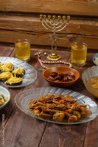 Shabbat table with traditional holiday food meat sweets wine menorah. Vertical photo