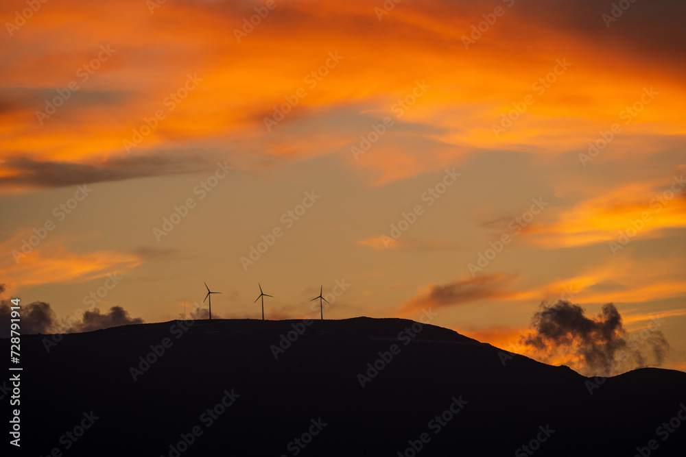 Clean energy power concept with wind turbine on top of a mountain during dramatic sunset in zakynthos, Greece