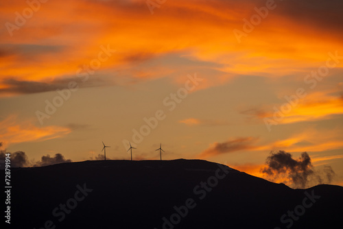 Obraz na płótnie Clean energy power concept with wind turbine on top of a mountain during dramatic sunset in zakynthos, Greece w salonie