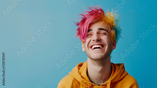 Happy young man with colored hair colorful clothes laughs. Cheerful young man smiling on colorful background. Smiling funny teen student, cool curly generation z teenager laughing