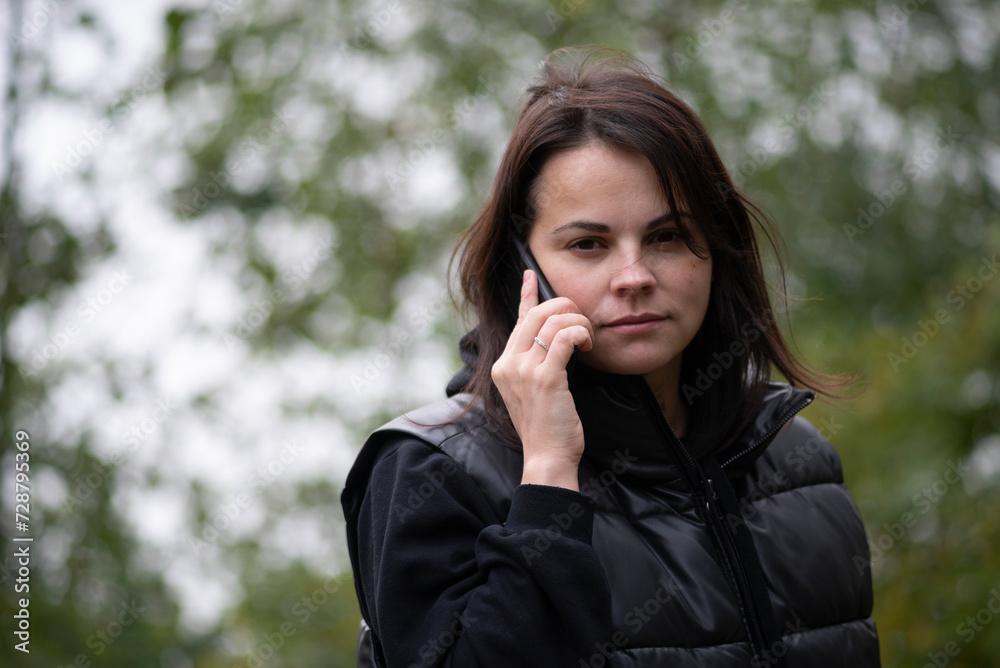 Portrait of a young woman talking on the phone in the park Portrait of a young woman talking on the phone in the park