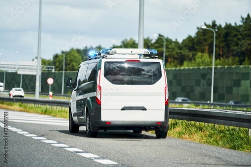 A police van with a mobile radar camera monitors the speed of traffic on a highway. A warning sign of speed limit and fine is placed on the road. A concept of road safety and enforcement.