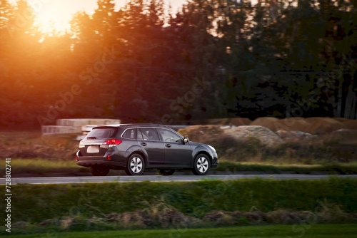 Driving a modern car in the golden hour of dusk. A scenic landscape of forest and road awaits the adventurous travelers. photo