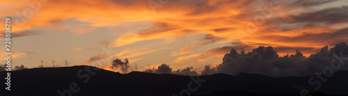 Obraz na płótnie Panorama shot of clean energy power concept with wind turbine on top of a mountain during dramatic sunset in zakynthos, Greece w salonie