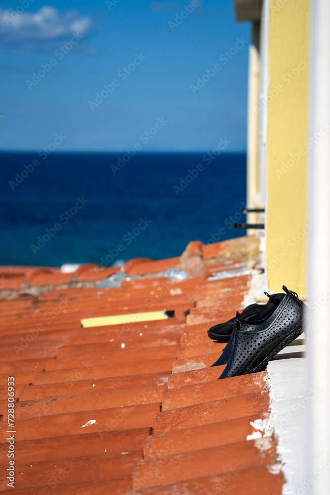 Rubber beach wear shoes are being dried out on a terrace against blue sea
