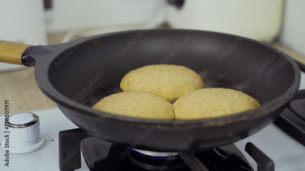 Making pumpkin apple cheesecakes. A woman places a glass lid on cheesecakes being cooked in a frying pan. Close-up. Making pumpkin apple cheesecakes. A woman places a glass lid on cheesecakes being cooked in a frying pan. Close-up.
