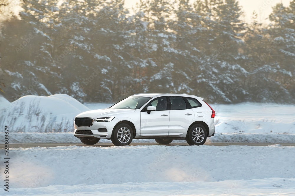 Winter’s embrace holds no barrier for this powerful SUV as it glides through the snowy terrain with grace and power showcasing man’s conquest over nature. White truck car on the winter snowy road.