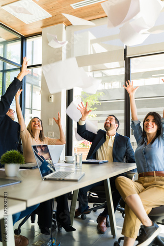 Group of businesspeople excited about the weekend throwing papers in the air photo