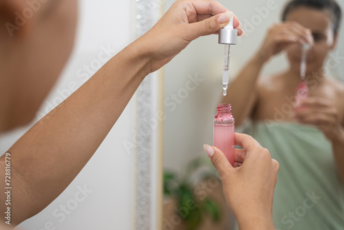 Anti-aging routine: In her home, a woman applies hyaluronic acid serum using a dropper, enhancing her skincare. 